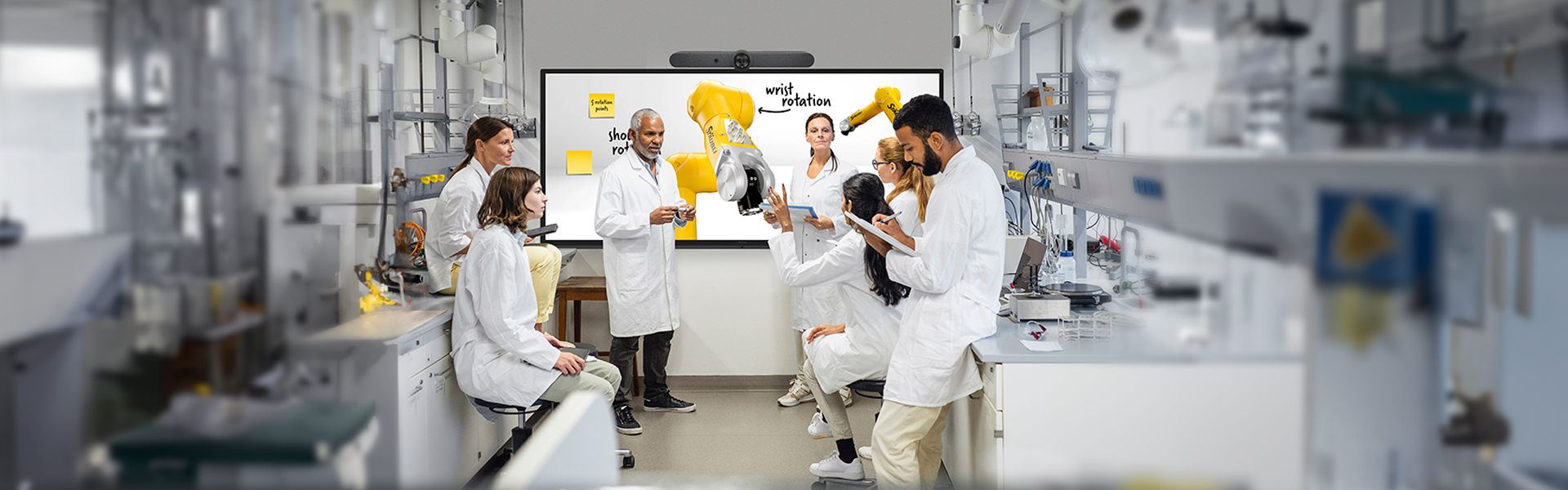 Equipo de trabajo reunido frente a una pantalla interactiva de gran formato con cámara de videoconferencia