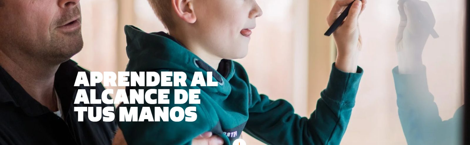 Un niño escribe sobre una pantalla interactiva acompañado por un docente